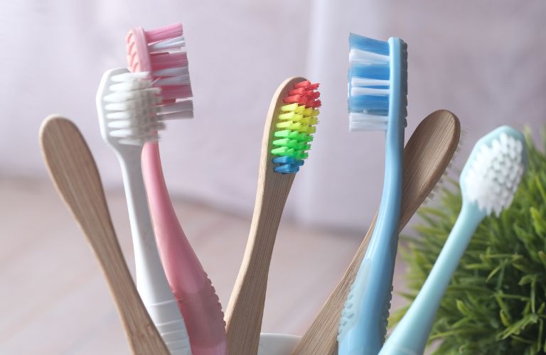 set of colorful toothbrushes in a cup on a bathroom countertop