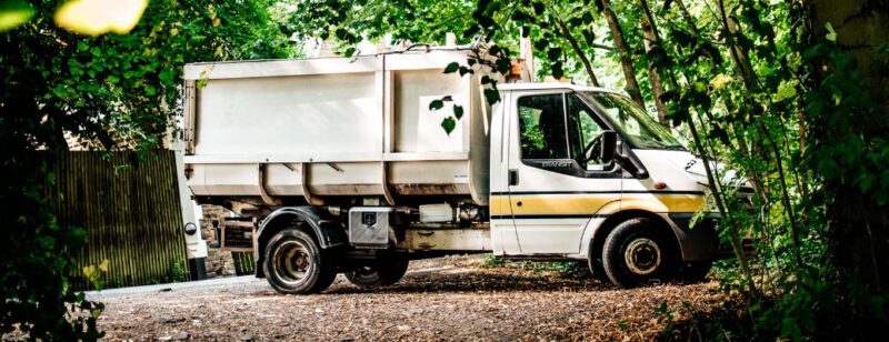 large dump truck parked near a wooden fence and trees