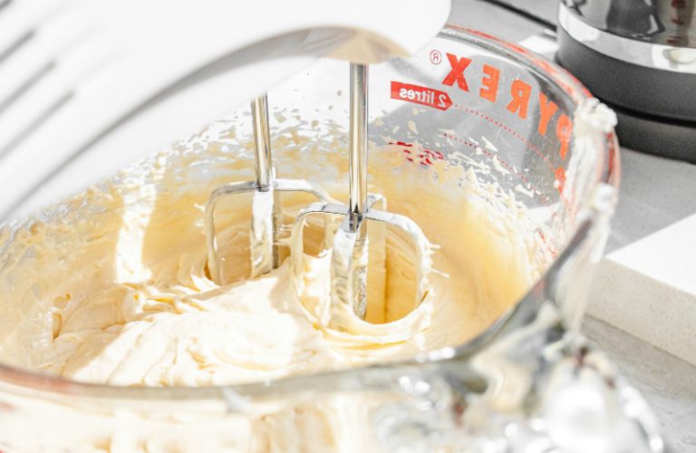 hand mixer mixing a batter in a glass measuring cup