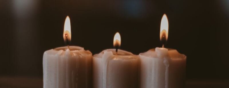 three white candles lined up and lit