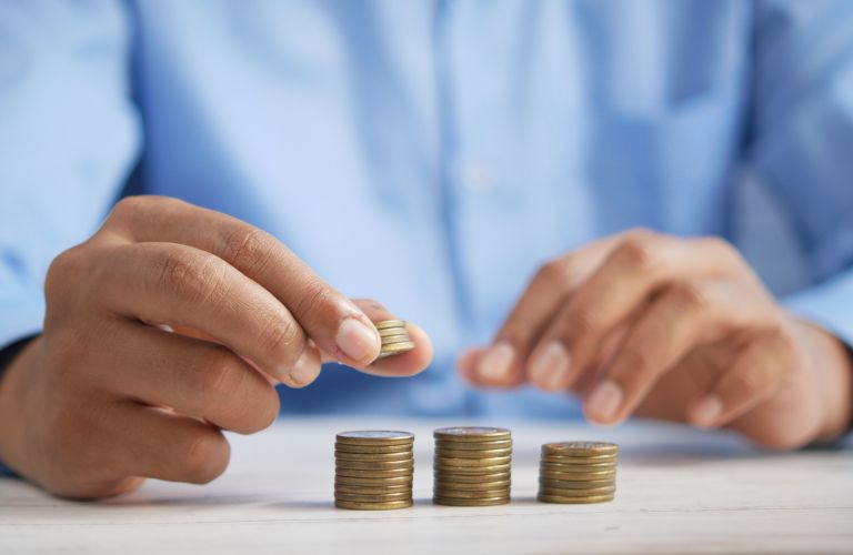 person in blue shirt stacking coins into three stacks